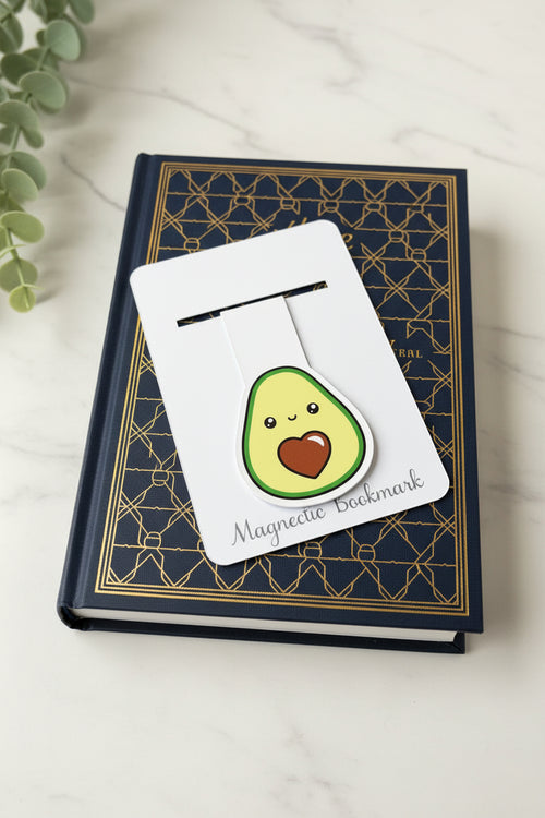 Magnetic bookmark shaped like an avocado on a decorative card with a plant in the background